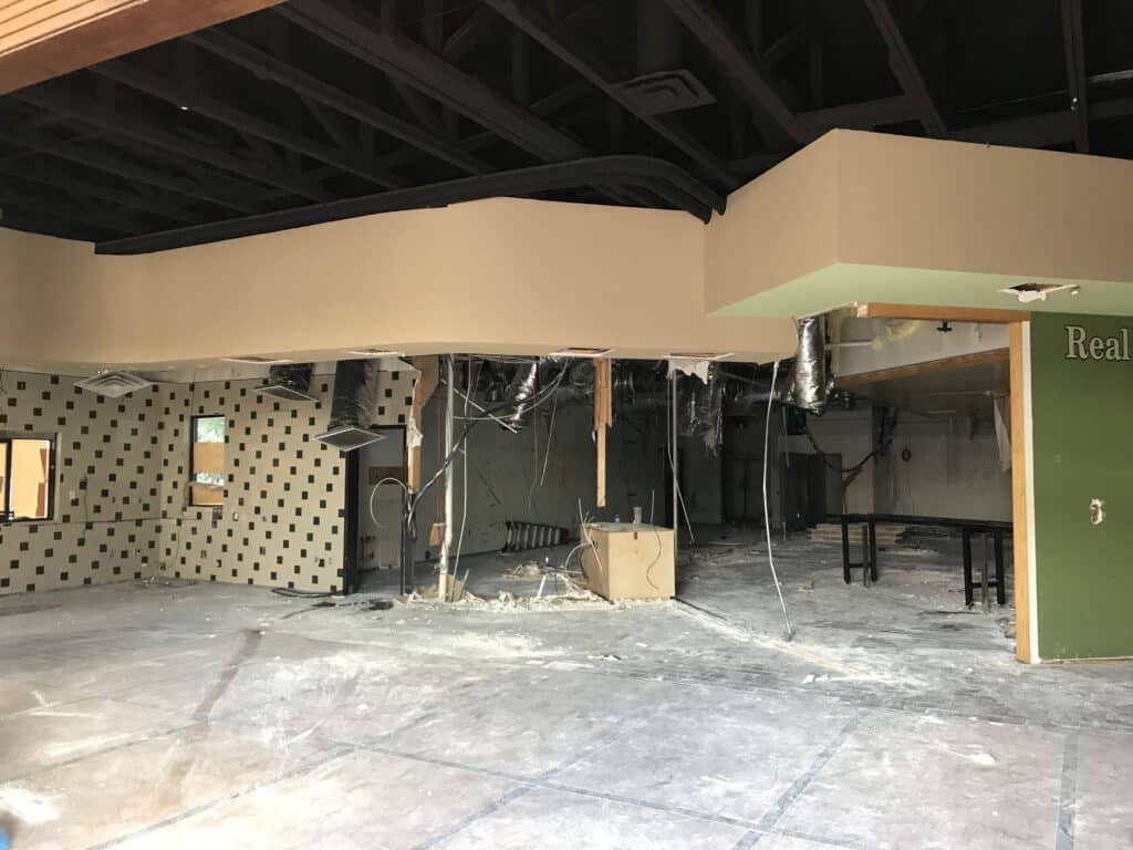 Interior demolition site with exposed ceiling and debris-covered floor.