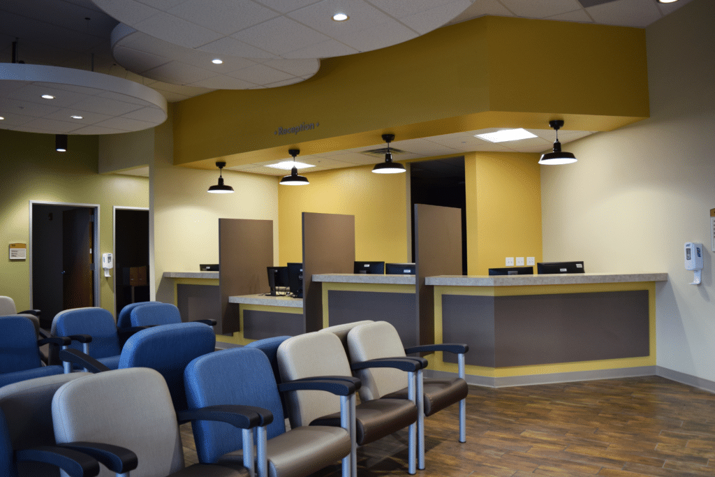 Modern medical office waiting area with reception desk and chairs.