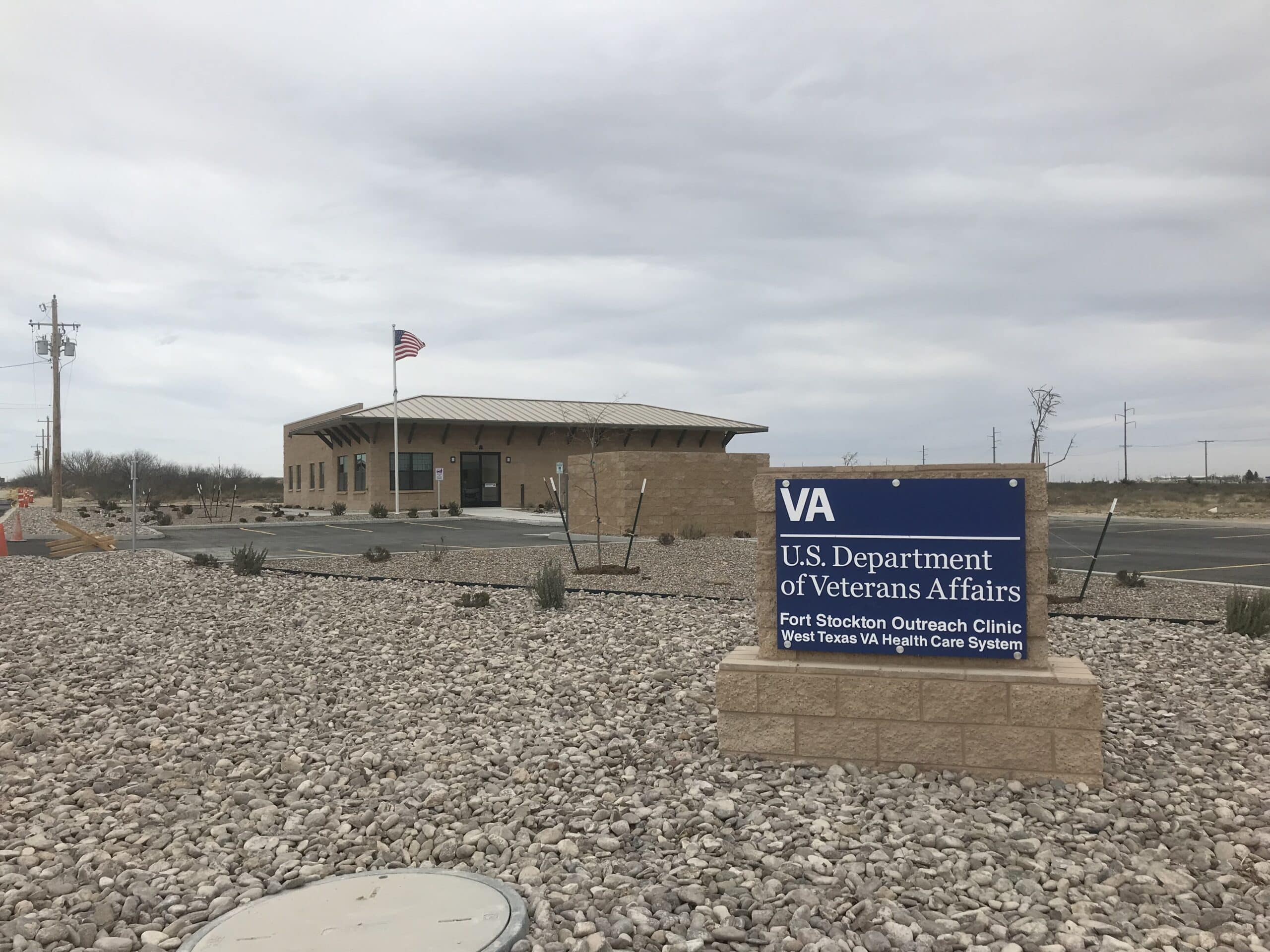 U.S. Department of Veterans Affairs Fort Stockton Outreach Clinic with American flag and sign in foreground.